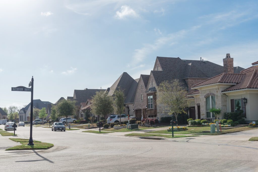 New development neighborhood near Dallas, Texas, America. Brand new two story house curbside front yard with sidewalk pathway and well trimmed landscape in early springtime. Sunny cloud blue sky